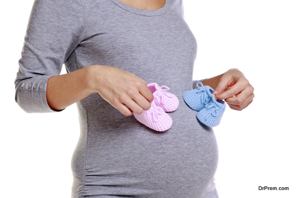 Pregnant woman holding baby booties.